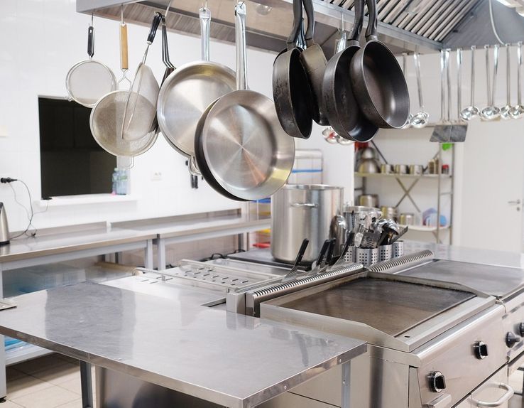 Una cocina con muchas ollas y sartenes colgando del techo.