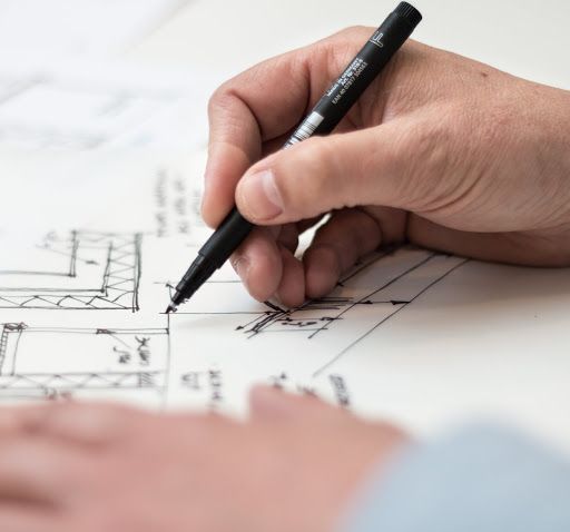 Una persona está escribiendo en un trozo de papel con un bolígrafo que dice 'Pentel'.