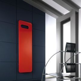 Un objeto rojo está colgado en una pared al lado de una silla.