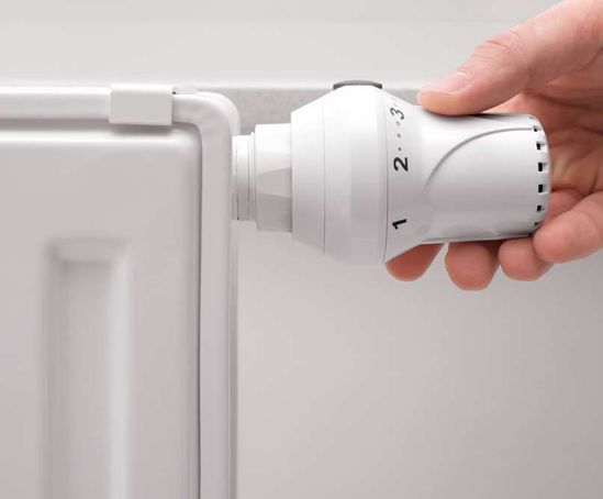 Una persona está ajustando un termostato en un radiador.