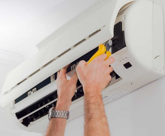 Un hombre que lleva un reloj está trabajando en un aire acondicionado.