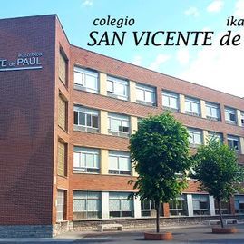 Un gran edificio de ladrillo con muchas ventanas y árboles frente a él.