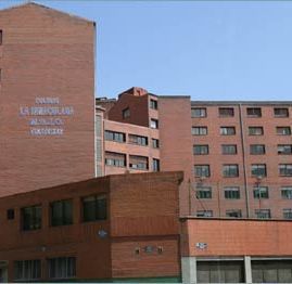 Un gran edificio de ladrillo con muchas ventanas y un cielo azul al fondo.
