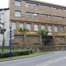 Un gran edificio de ladrillo con muchas ventanas está al lado de una carretera.