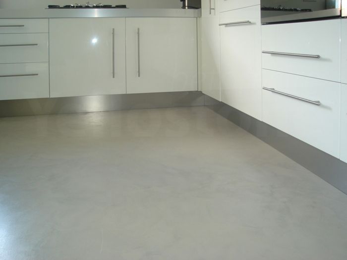 Eine Küche mit weißen Schränken und einem grauen Boden