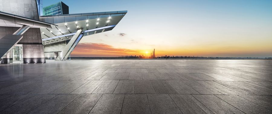 Ein leerer Parkplatz mit einem Gebäude im Hintergrund bei Sonnenuntergang.