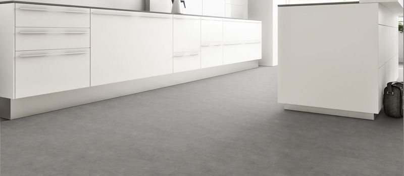 Eine Küche mit weißen Schränken und grauem Boden.