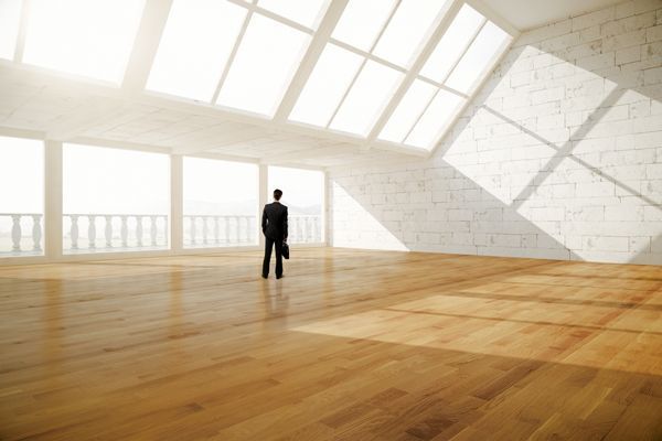 Ein Mann steht mit einer Aktentasche in einem leeren Raum.