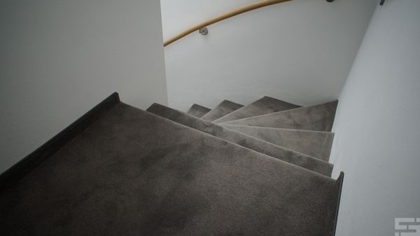 Eine Treppe mit Holzhandlauf und Teppichboden.