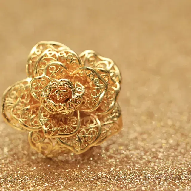 Un anillo de oro en forma de flor está sobre una mesa.