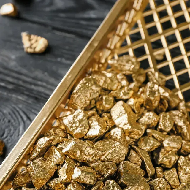 Una cesta llena de pepitas de oro sobre una mesa de madera.