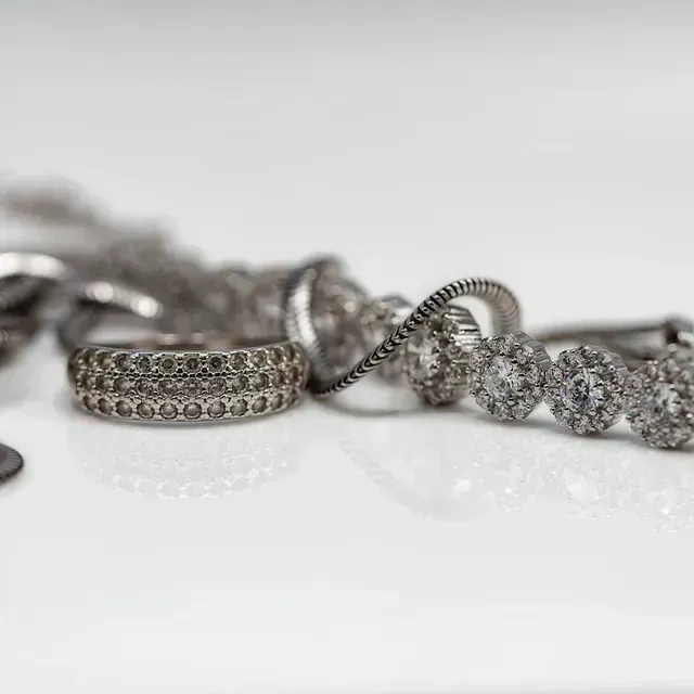 Un primer plano de un montón de anillos de plata sobre una superficie blanca.