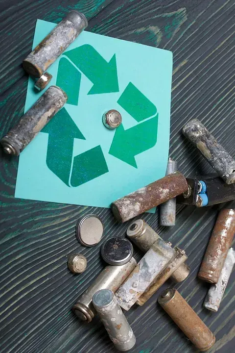 Una pila de baterías viejas junto a un símbolo de reciclaje