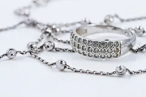 Un primer plano de un anillo y un collar sobre una superficie blanca.
