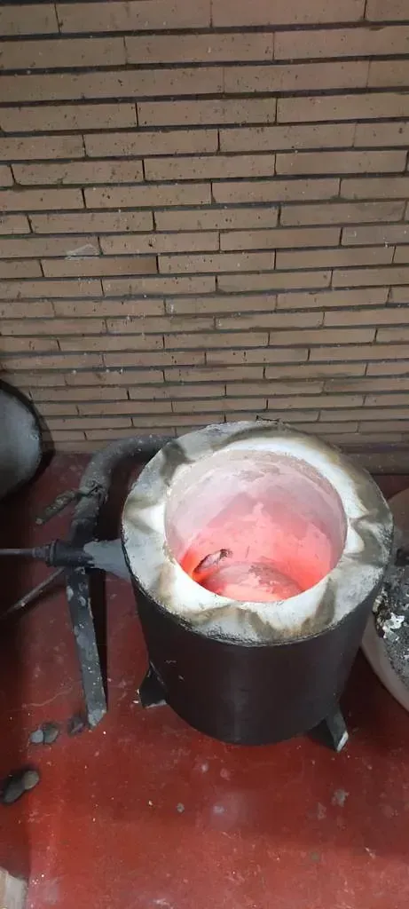 Una olla grande llena de líquido rojo reposa sobre un suelo rojo delante de una pared de ladrillos.