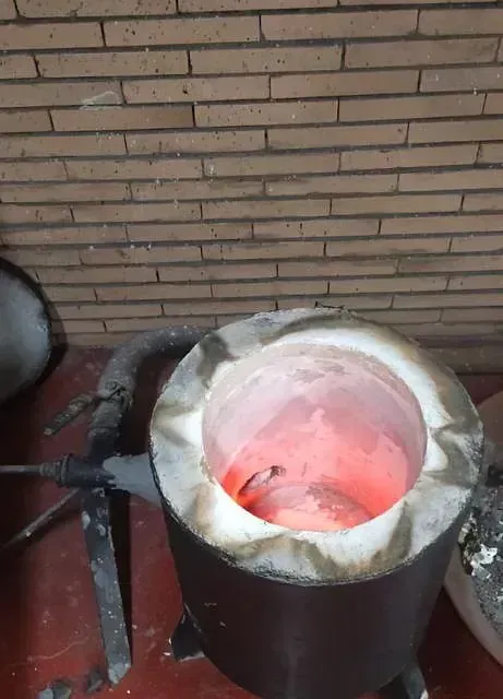 Detrás de un horno hay una pared de ladrillos con llamas rojas saliendo de él.