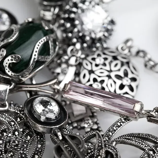 Un montón de joyas de plata que incluyen una piedra verde.