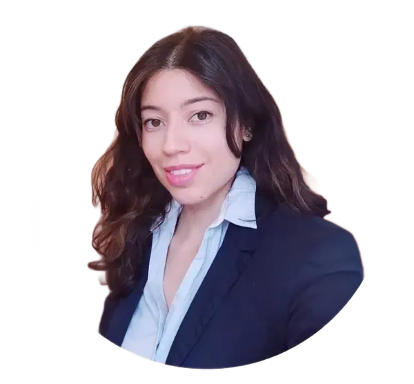 Mujer de cabello oscuro y rizado sonriendo y sosteniendo un micrófono con el brazo levantado. Lleva una blusa roja estampada.