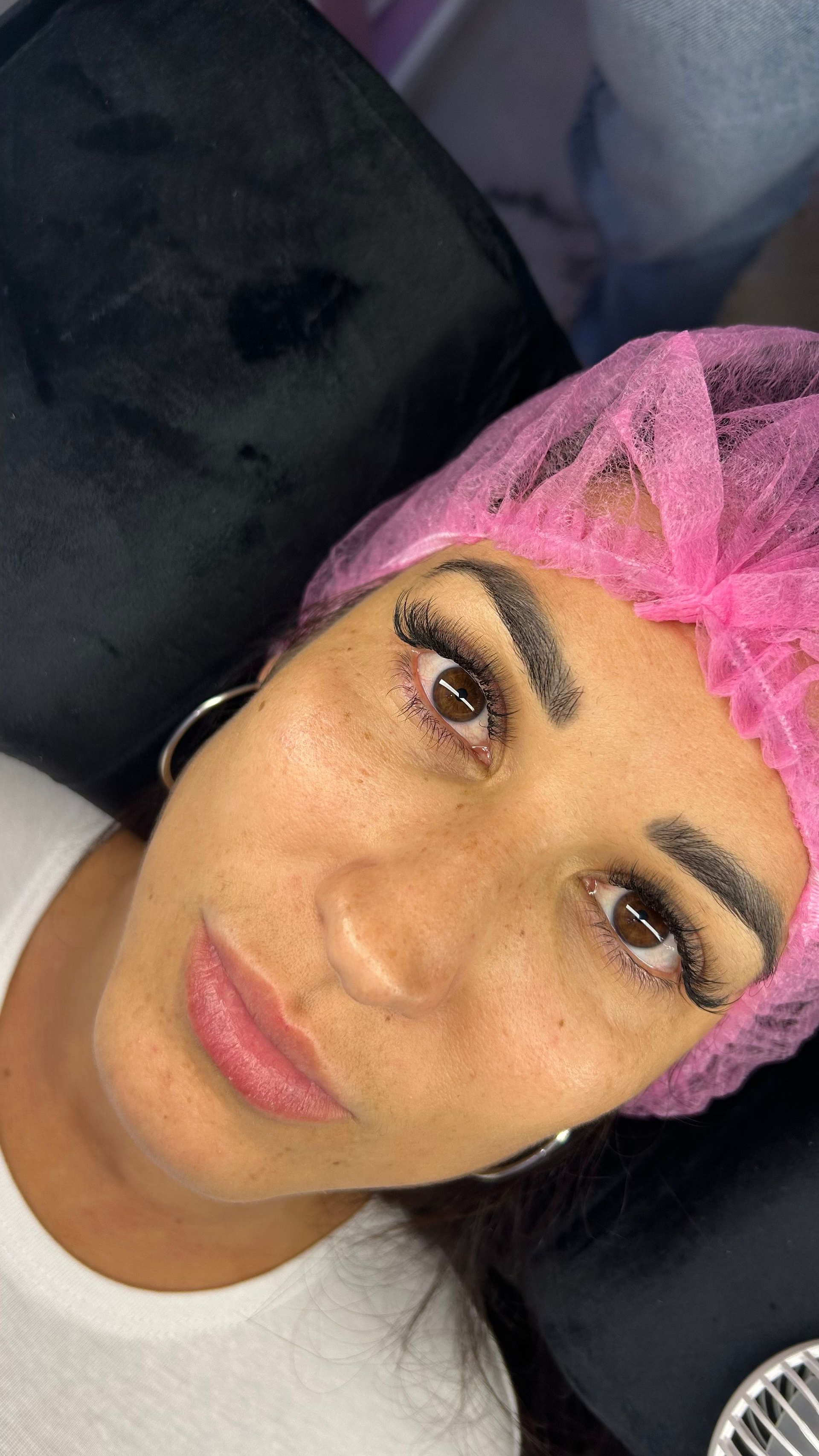 Mujer con cejas oscuras y pestañas pobladas, con gorra de red rosa.