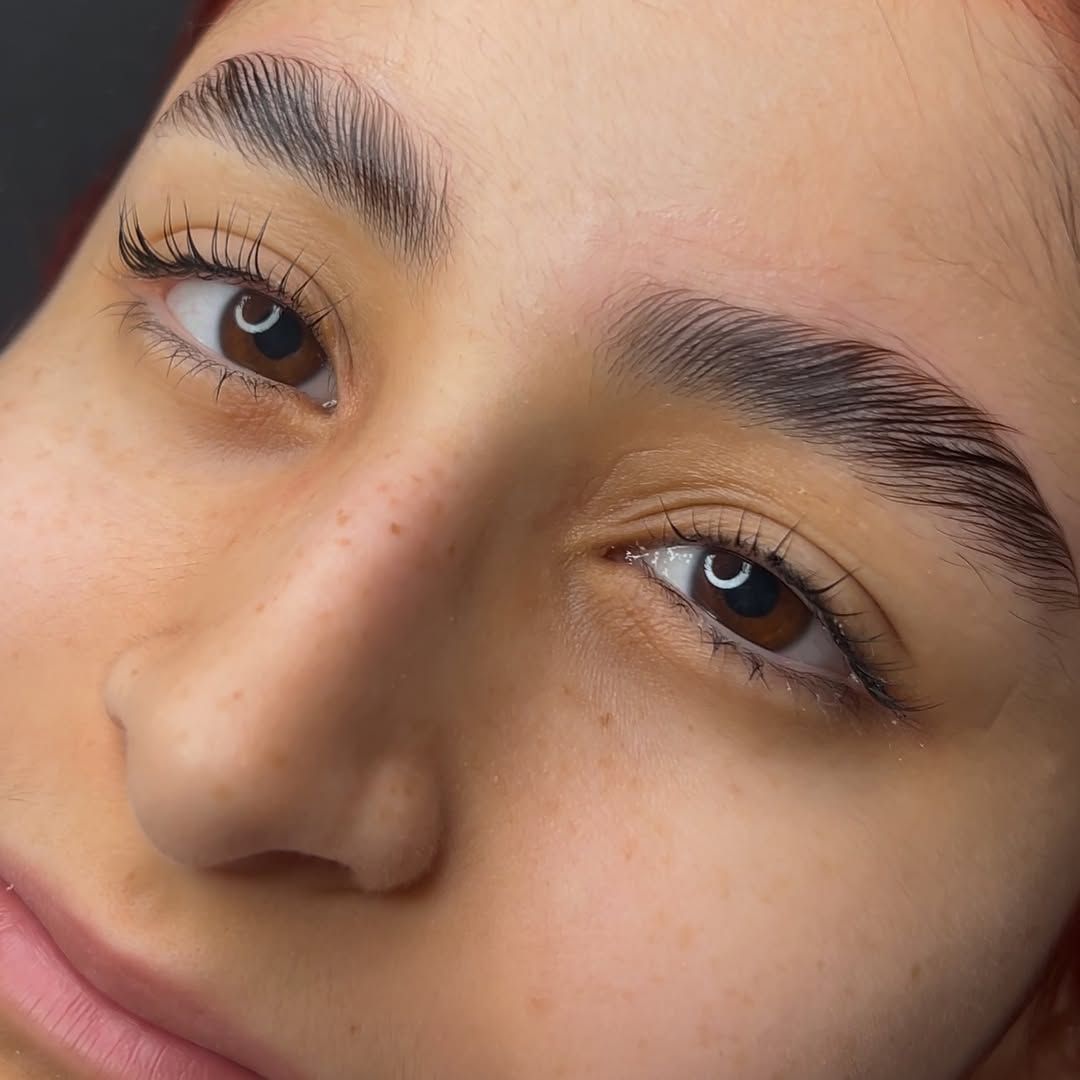 Primer plano de una persona con cejas y pestañas arregladas, ojos marrones y piel clara.