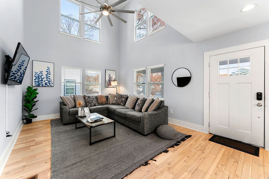A living room with a couch , coffee table , television and ceiling fan.