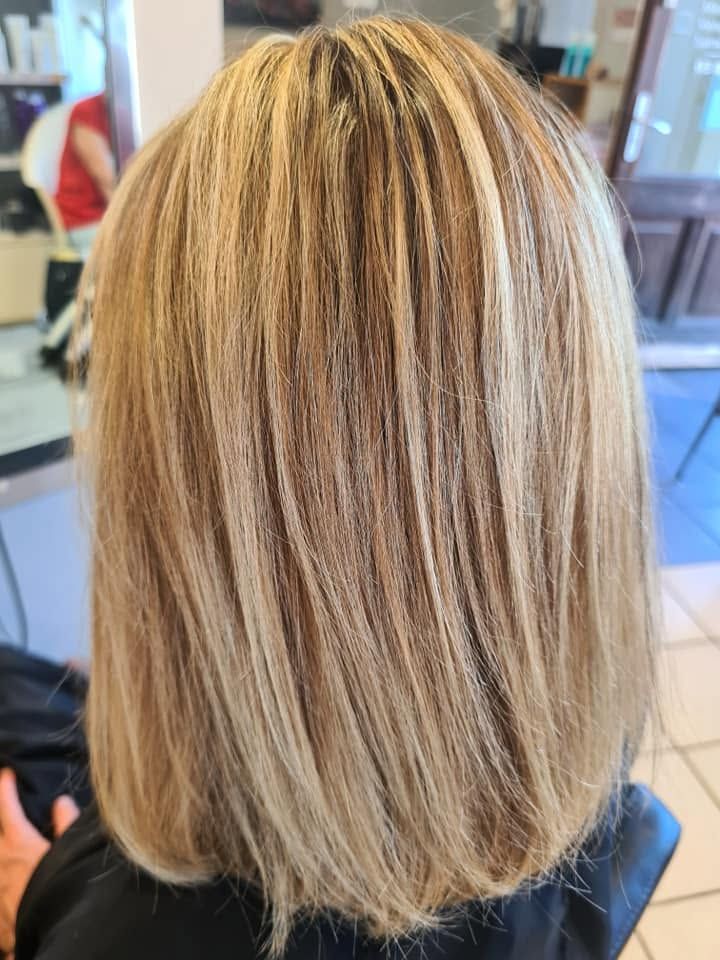 Coupe au carré blonde avec des mèches foncées, vue de dos dans un salon de coiffure.