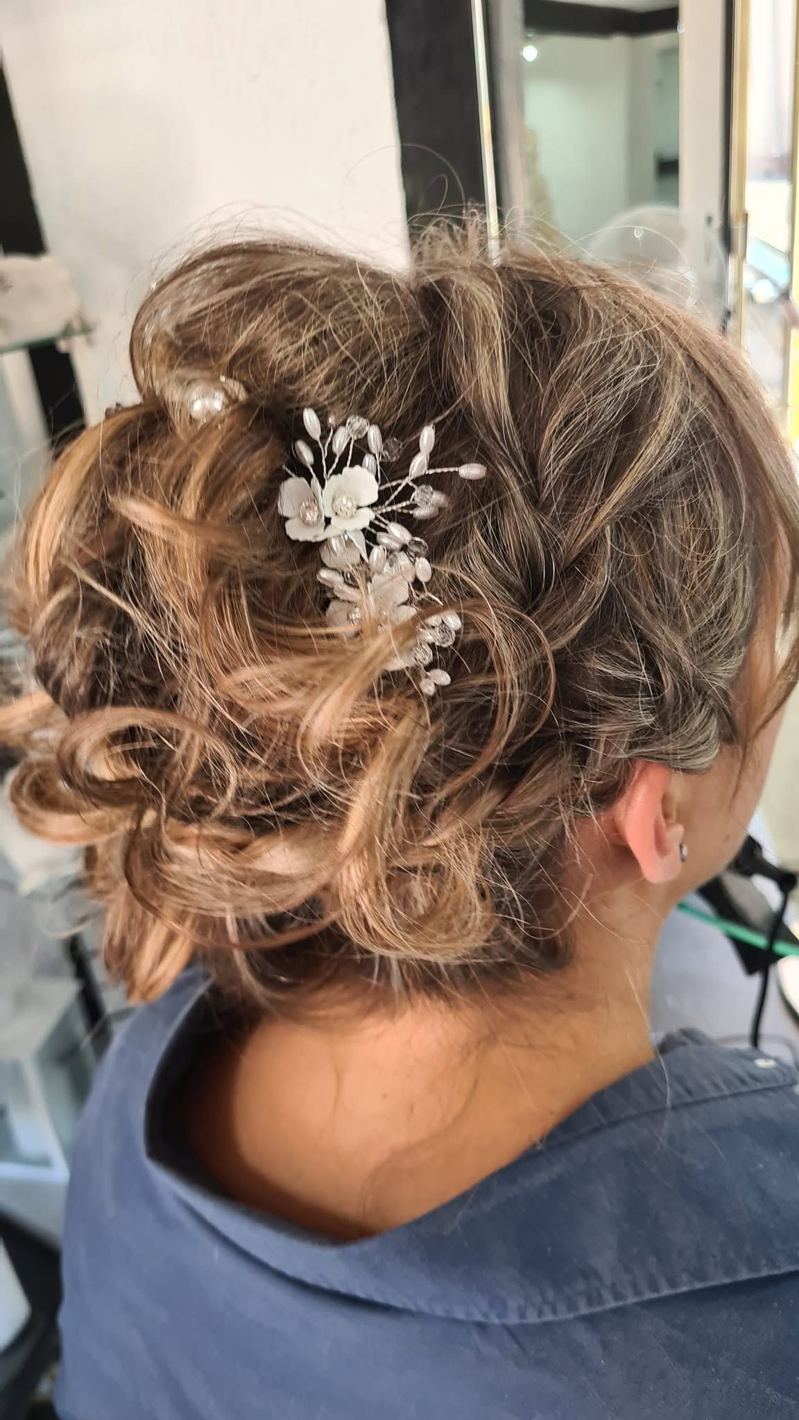 Chignon avec mèches bouclées et barrette décorative, vu de dos.