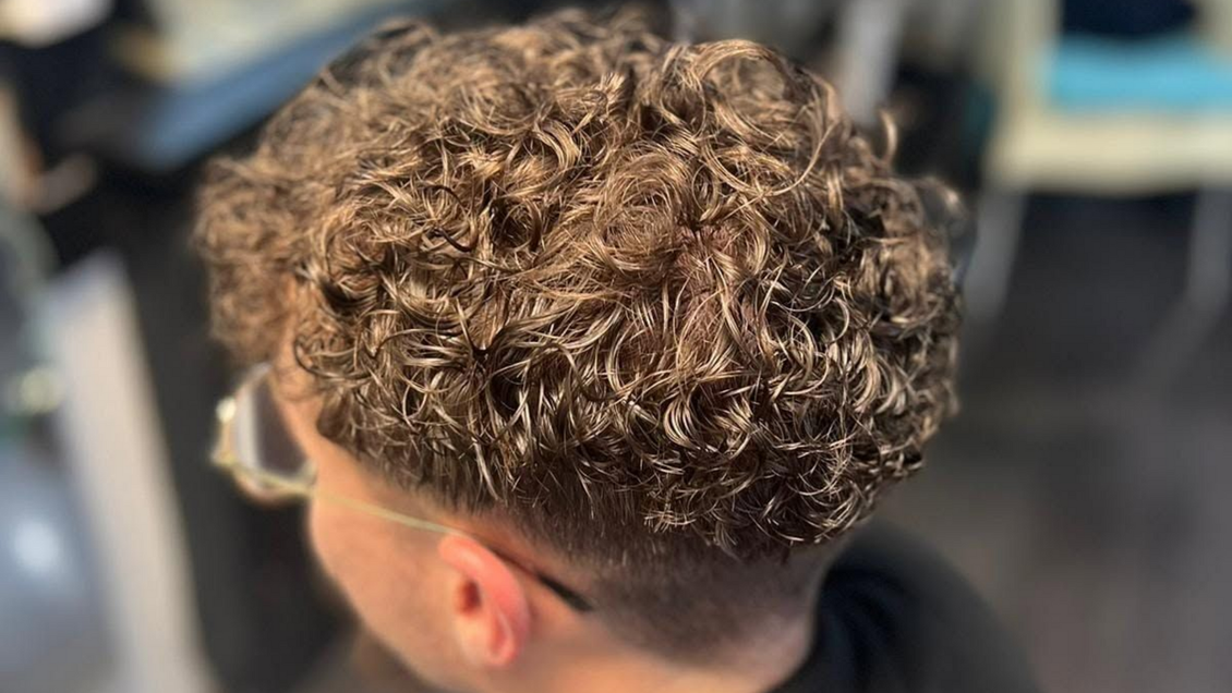 Gros plan sur une coupe de cheveux bouclés avec les côtés dégradés dans un salon de coiffure