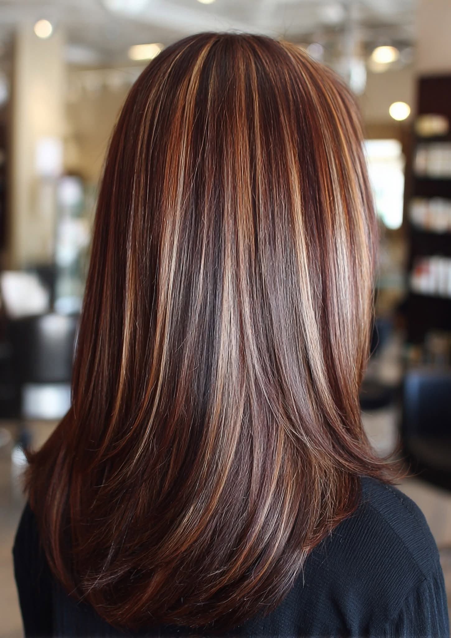 Des cheveux bruns mi-longs avec des mèches blondes, lissés en salon.
