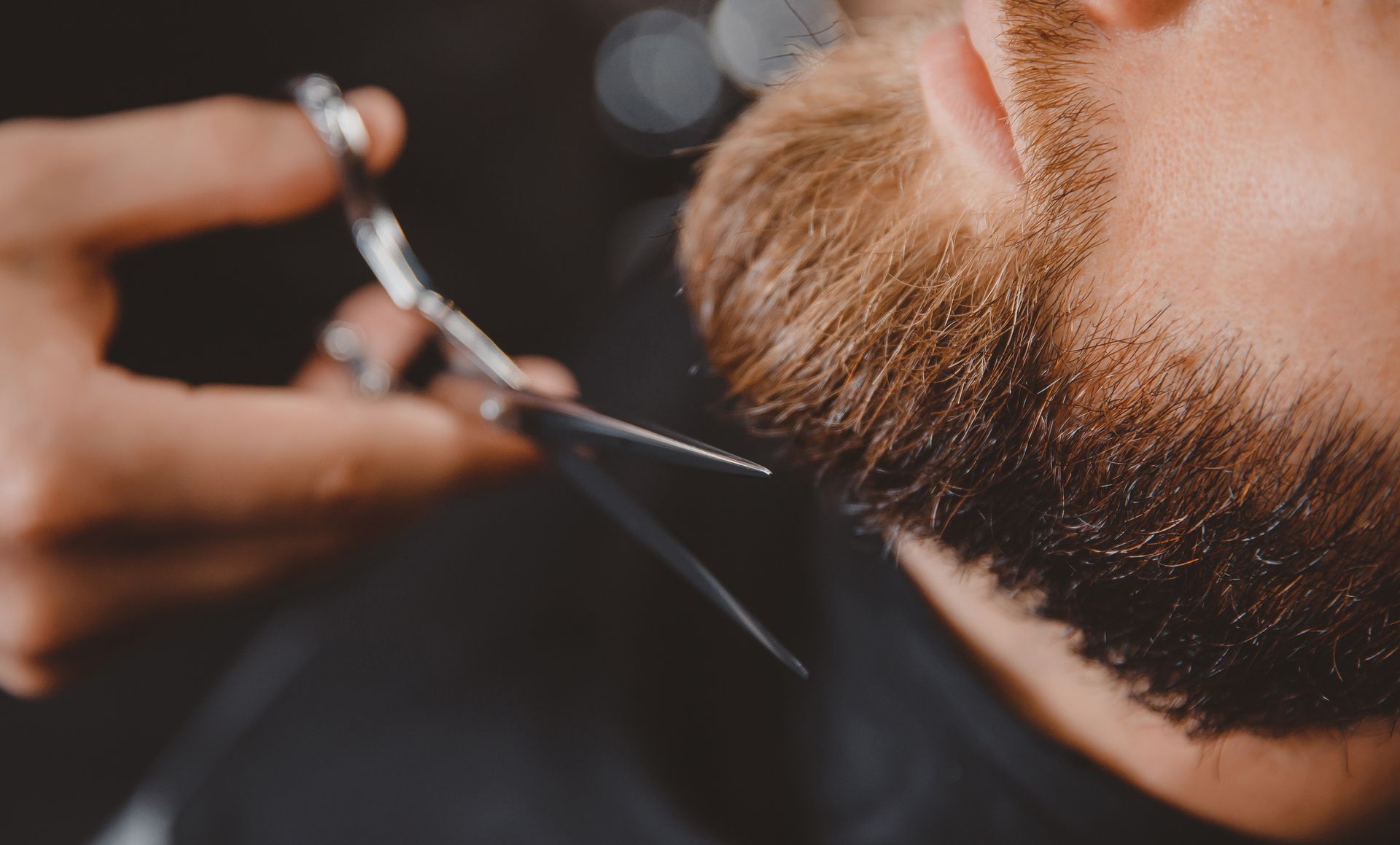 Gros plan sur une taille de barbe aux ciseaux chez un barbier.