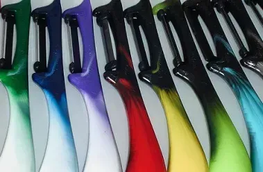 Nahaufnahme von bunten Gemüseschälern in einer Reihe, mit Griffen in Farbverlauf von Grün, Blau, Lila, Rot und Gelb.