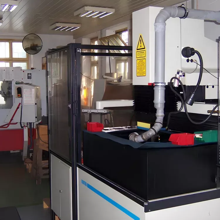 Eine Industriemaschine mit einem grauen Rohr in einer hell erleuchteten Werkstatt.