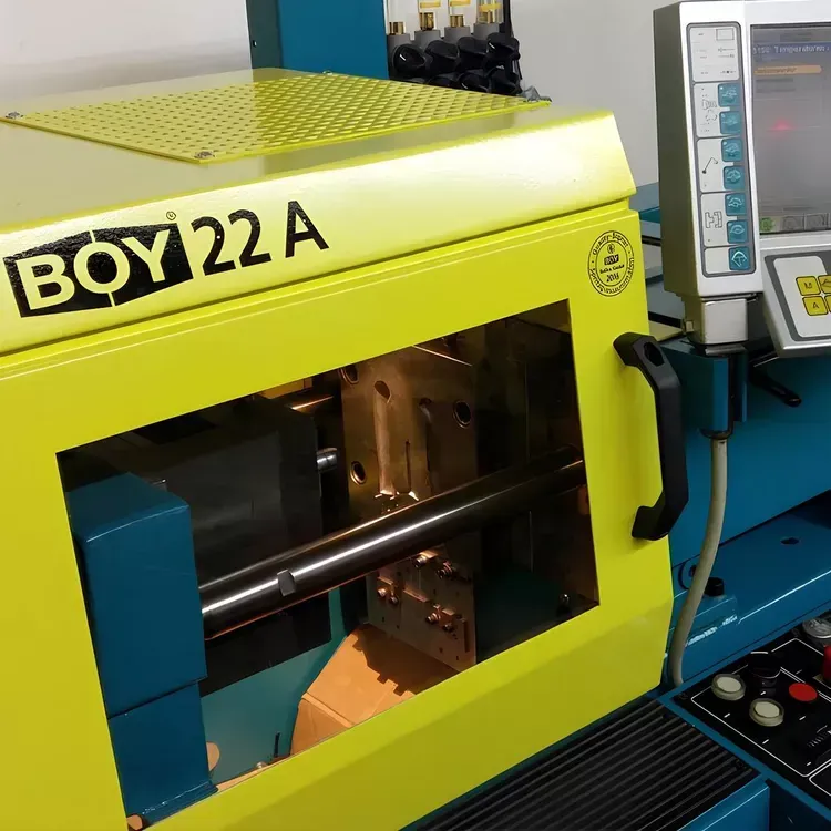 Gelbe und blaue BOY 22 A Spritzgießmaschine mit offener Kavität.