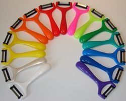 Ein Regenbogenbogen aus bunten Gemüseschälern, angeordnet auf einer weißen Fläche.