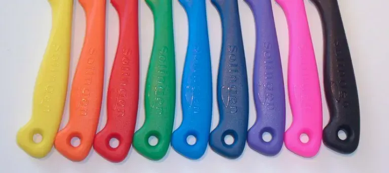 Neun farbenfrohe Griffe in einer Reihe angeordnet: gelb, orange, rot, grün, blau, lila, rosa und schwarz.