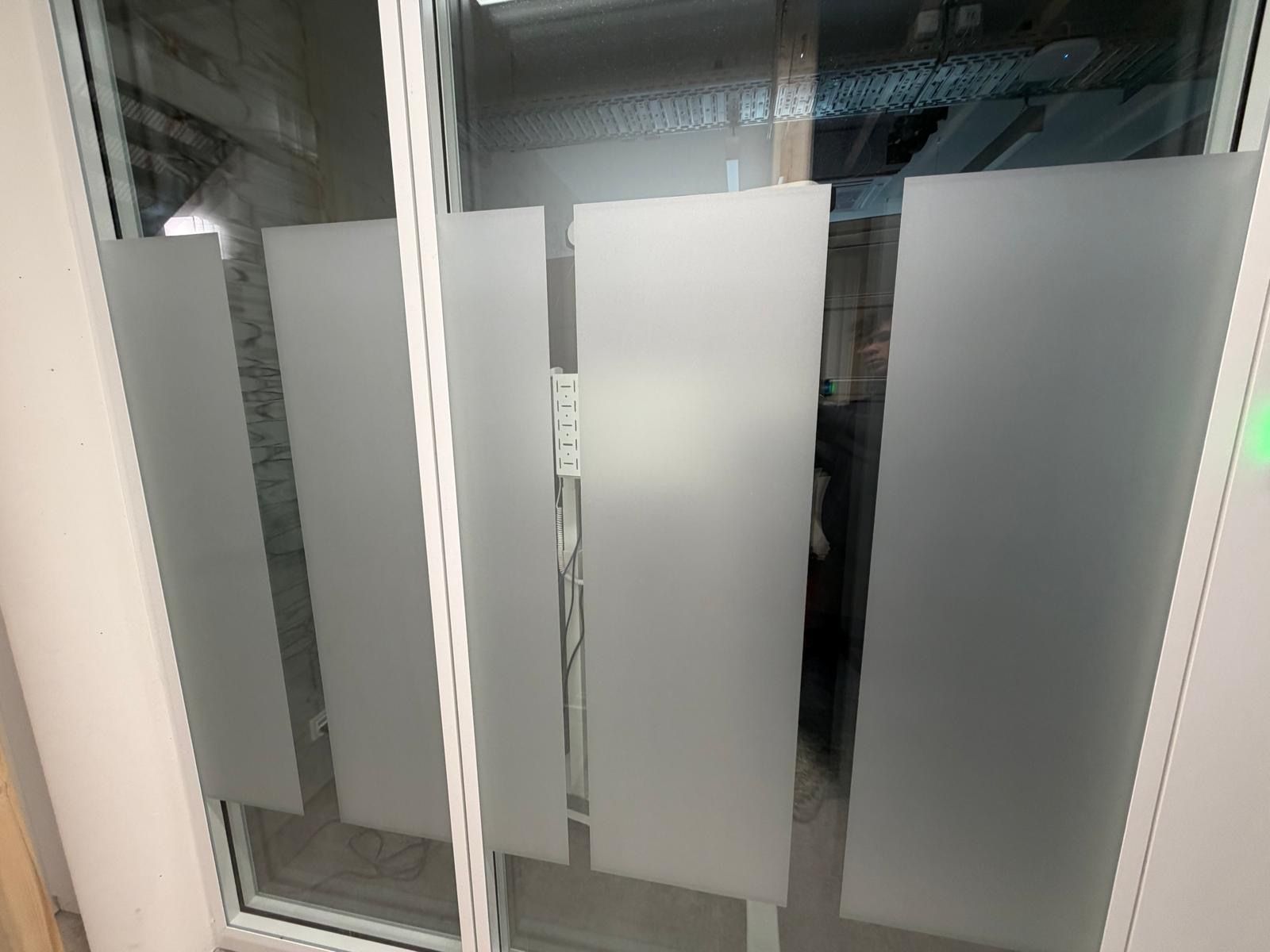 Bürotrennwände aus Milchglas mit Metallrahmen und einer Türöffnung in der Mitte