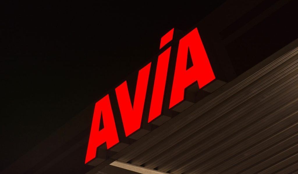 Rotes AVIA-Schild an einer dunklen Gebäudefassade bei Nacht