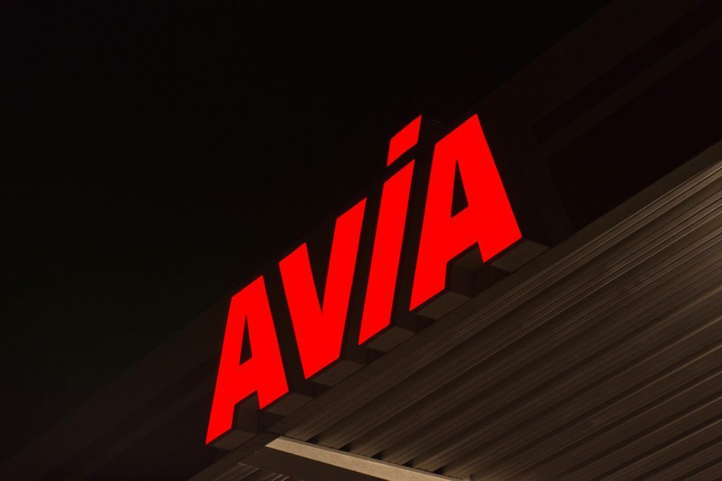 Ein rotes AVIA-Schild leuchtet nachts an der dunklen Fassade eines Gebäudes.