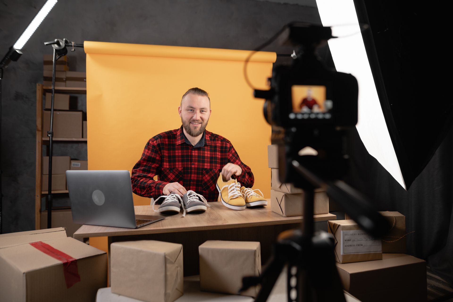 Ein Mann filmt eine Rezension an einem Schreibtisch mit Turnschuhen und Kamera in einem Studio.