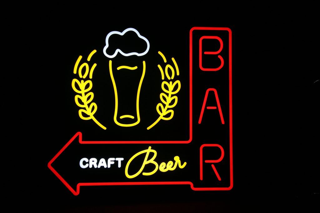Neonreklame für Craft-Bier mit Bierglas, Hopfenkranz und rotem Pfeil, der nach links in Richtung BAR zeigt.