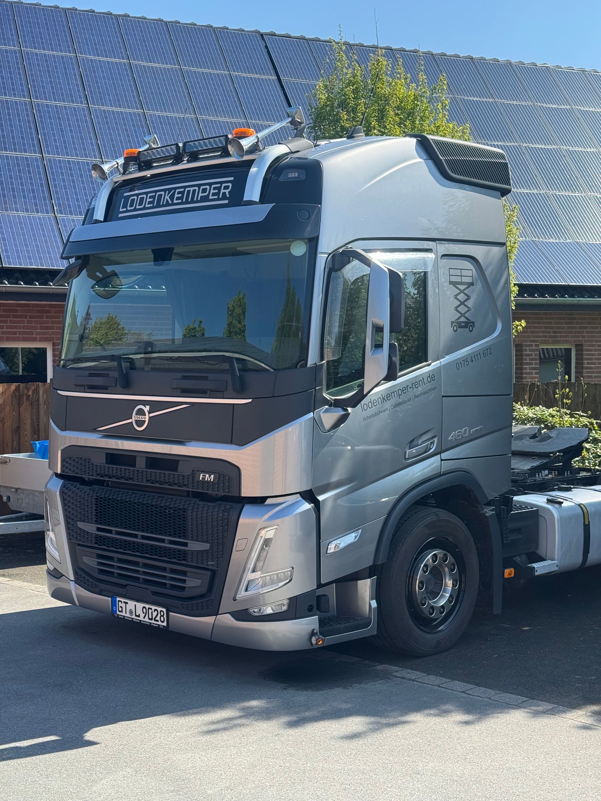 Ein silberner Volvo-Sattelzug parkt an einem sonnigen Tag neben Solarpaneelen.