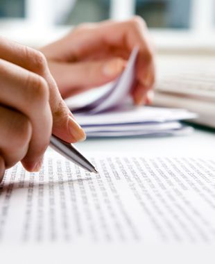 Una persona está escribiendo en un trozo de papel con un bolígrafo.