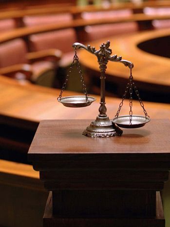 Una balanza de la justicia se encuentra sobre una mesa de madera en una sala de audiencias.