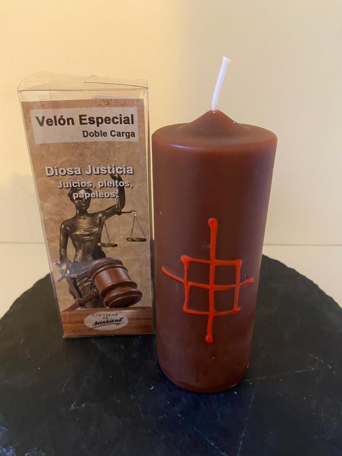 Una vela roja está sobre una mesa al lado de una caja.