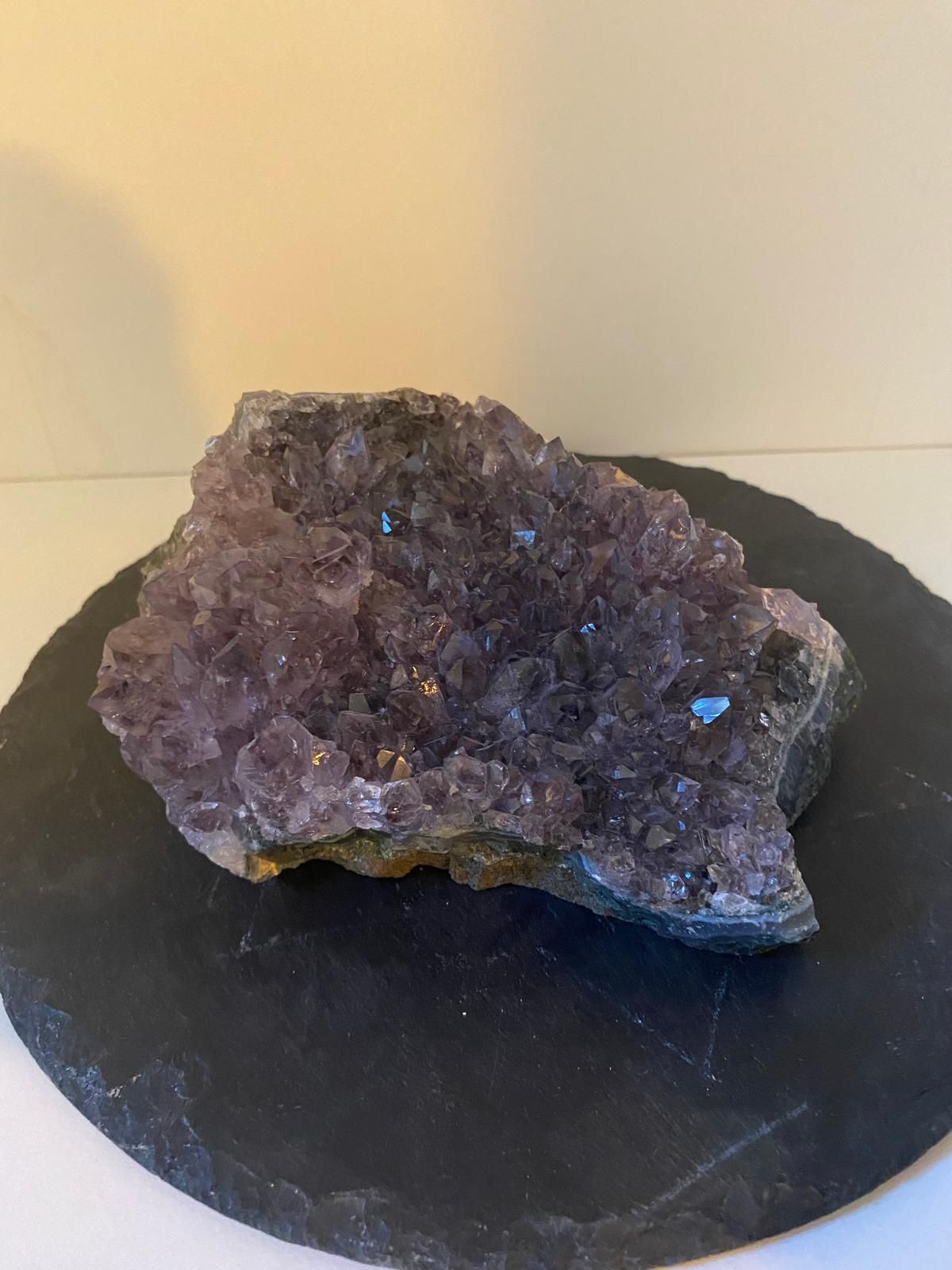 Un gran trozo de amatista reposa sobre una placa negra.