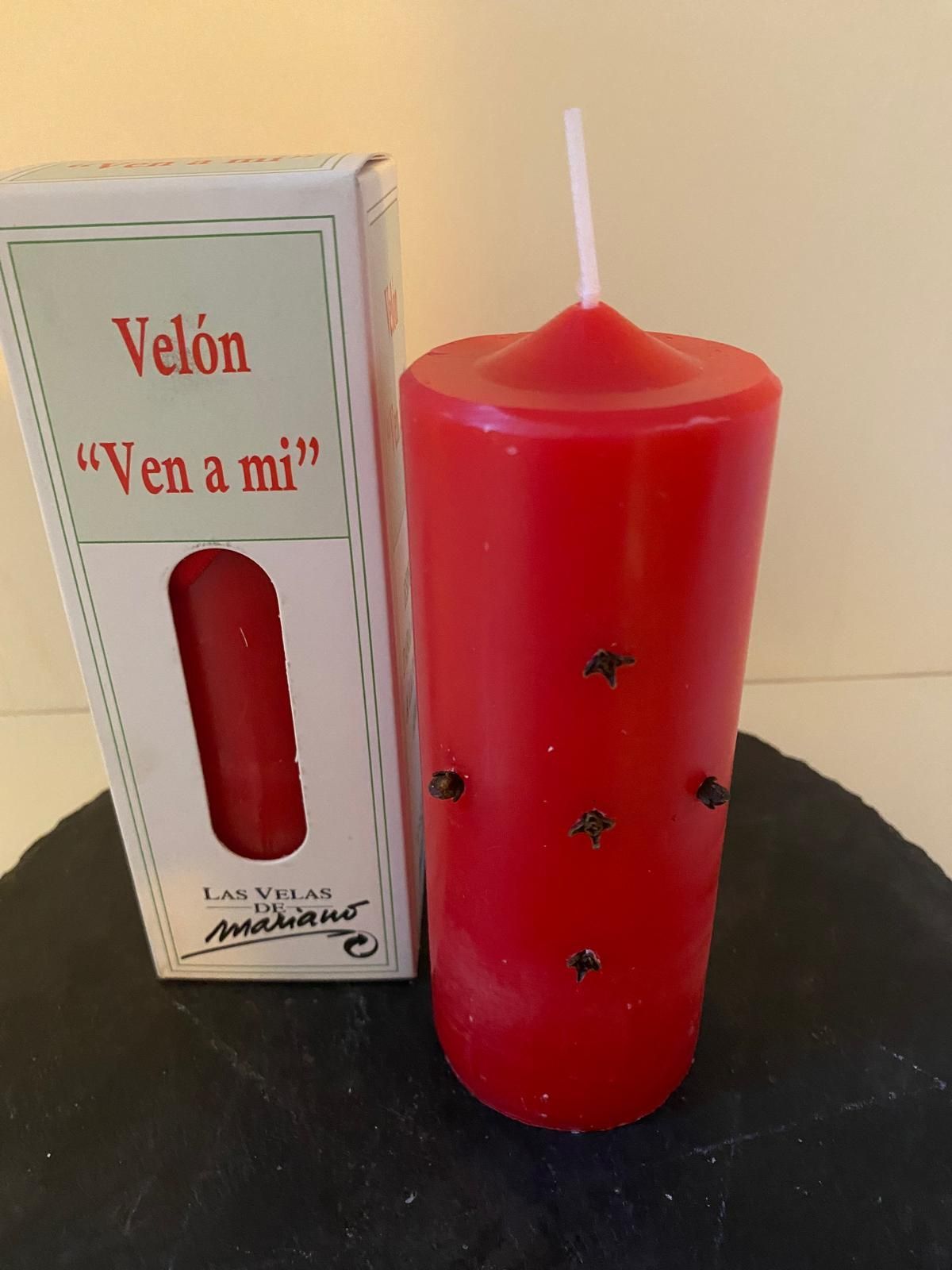 Una vela roja al lado de un recuadro que dice velon ven a mi