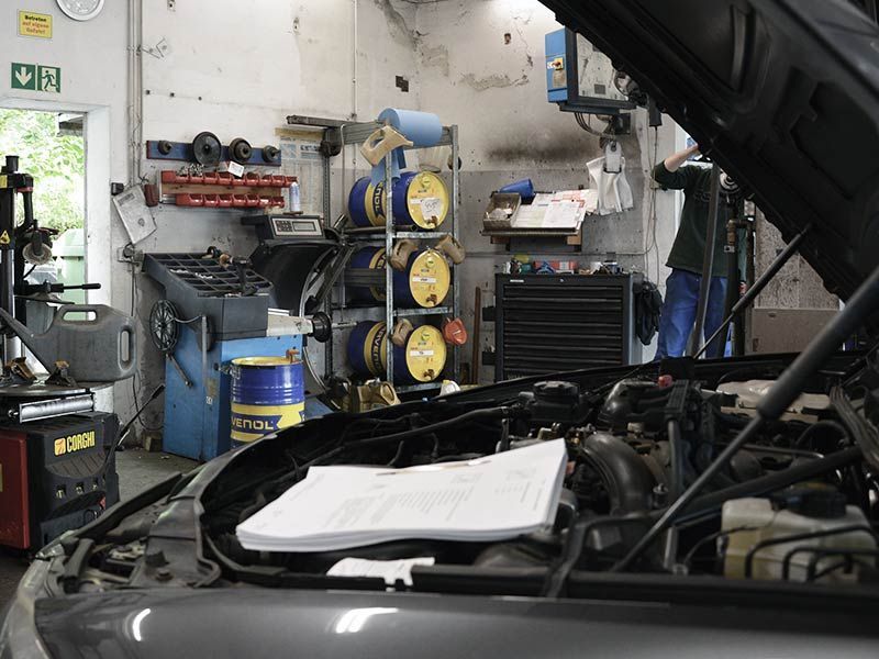 Ein Mann arbeitet in einer Garage bei geöffneter Motorhaube an einem Auto