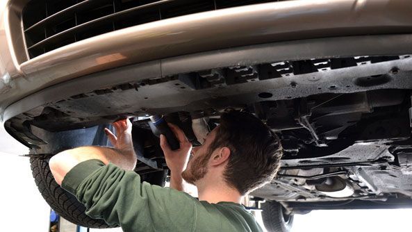 Ein Mann arbeitet an der Unterseite eines Autos.