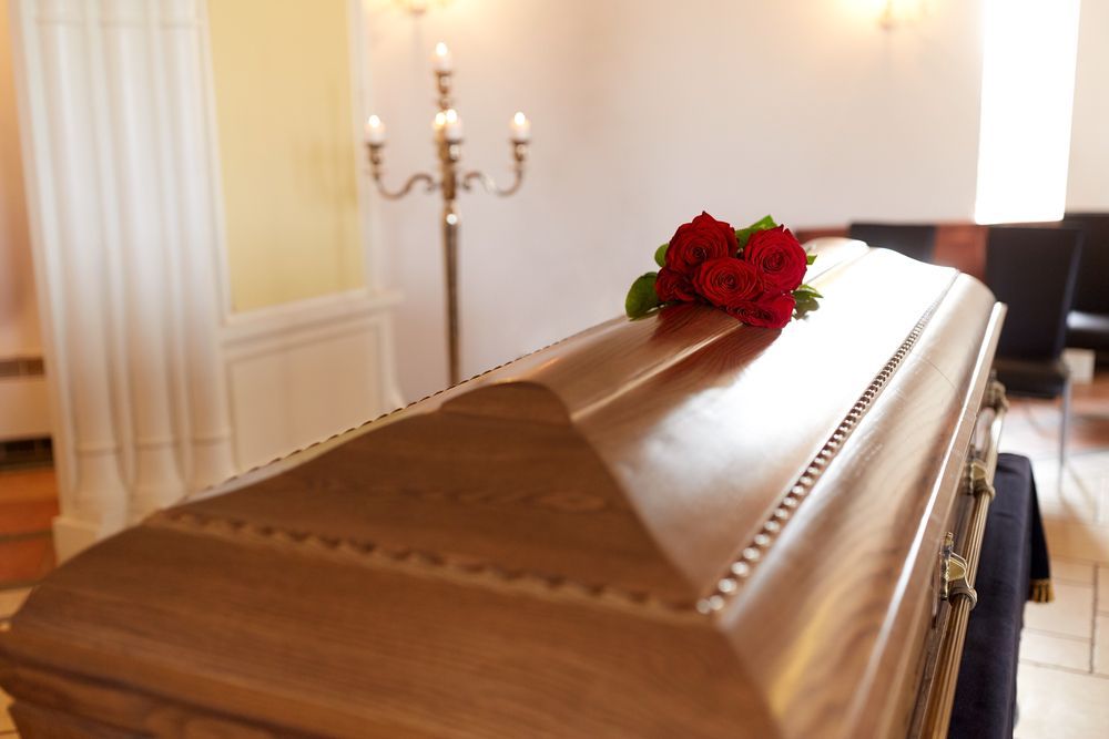 Un ataúd de madera con rosas rojas encima, en una funeraria.