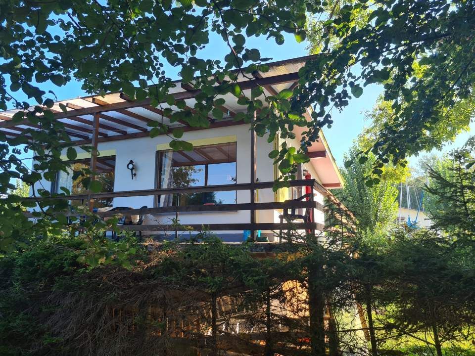 Une maisonnette blanche de plain-pied avec une terrasse en bois et un toit de porche.